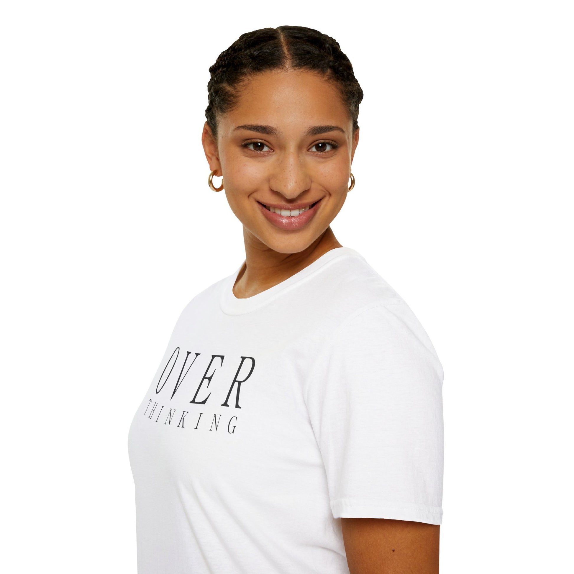 Frau trägt weißes T-Shirt mit schwarzem minimalistischen Schriftzug „OVERTHINKING“, sitzt entspannt auf einem Stuhl und lächelt
