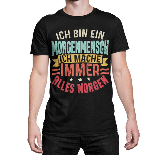 Mann trägt Schwarzes T-Shirt mit Spruch „Ich bin ein Morgenmensch – Ich mache immer alles morgen“ in bunten Retro-Farben