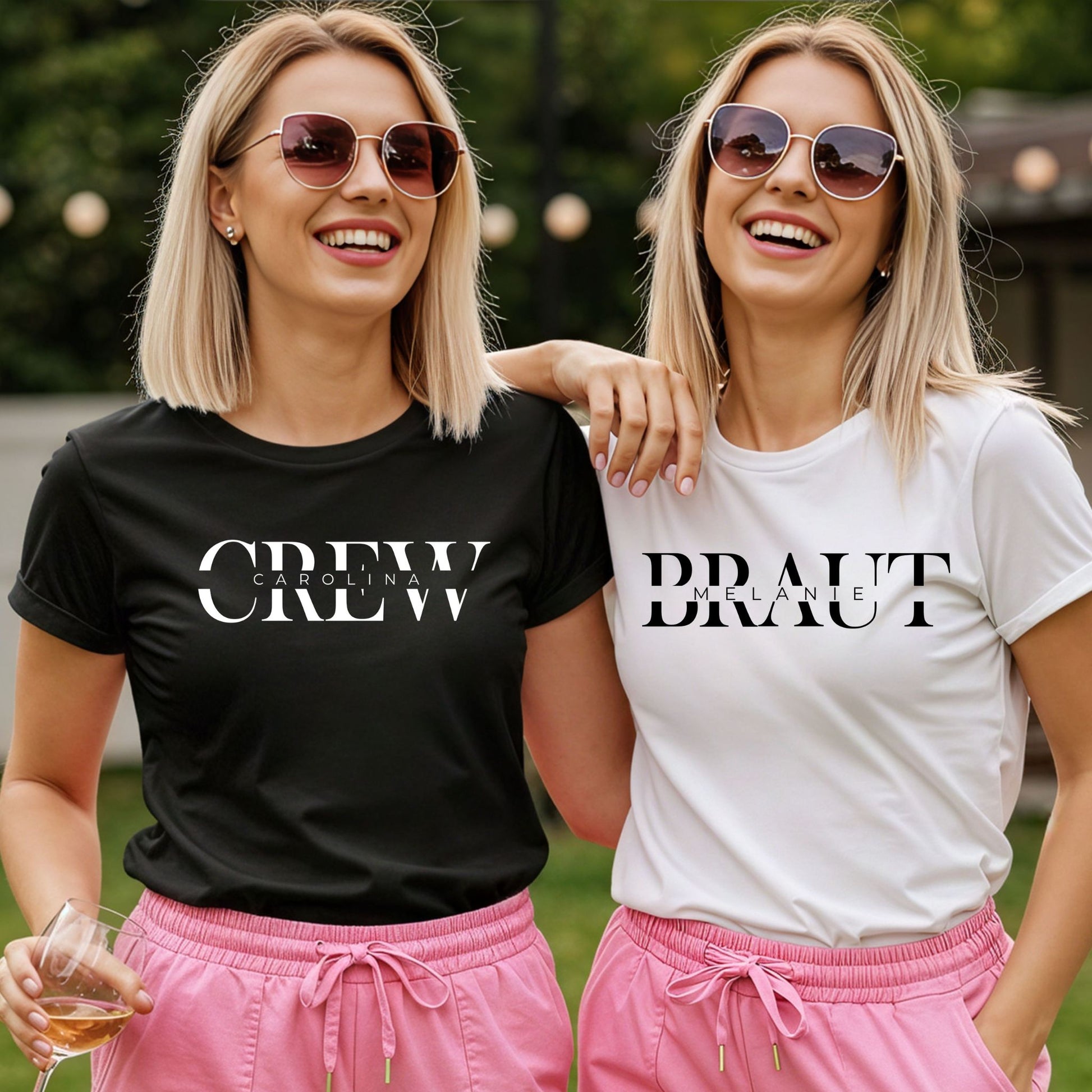 Zwei Frauen mit JGA Shirts: weißes T-Shirt mit „Braut Melanie“ und schwarzes Shirt mit „Crew Carolina“, beide tragen pinke Shorts