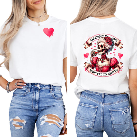 Frauen tragen weißes T-Shirt mit kleinem Herz vorne und großem Skelett-Print mit dem Spruch „Allergic to Love – Addicted to Shots“ auf dem Rücken
