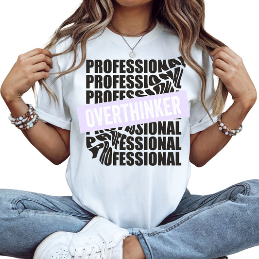 Frau trägt im sitzen Professional Overthinker T-Shirt in Weiß, lustiges Statement Shirt im minimalistischen Design für Männer und Frauen