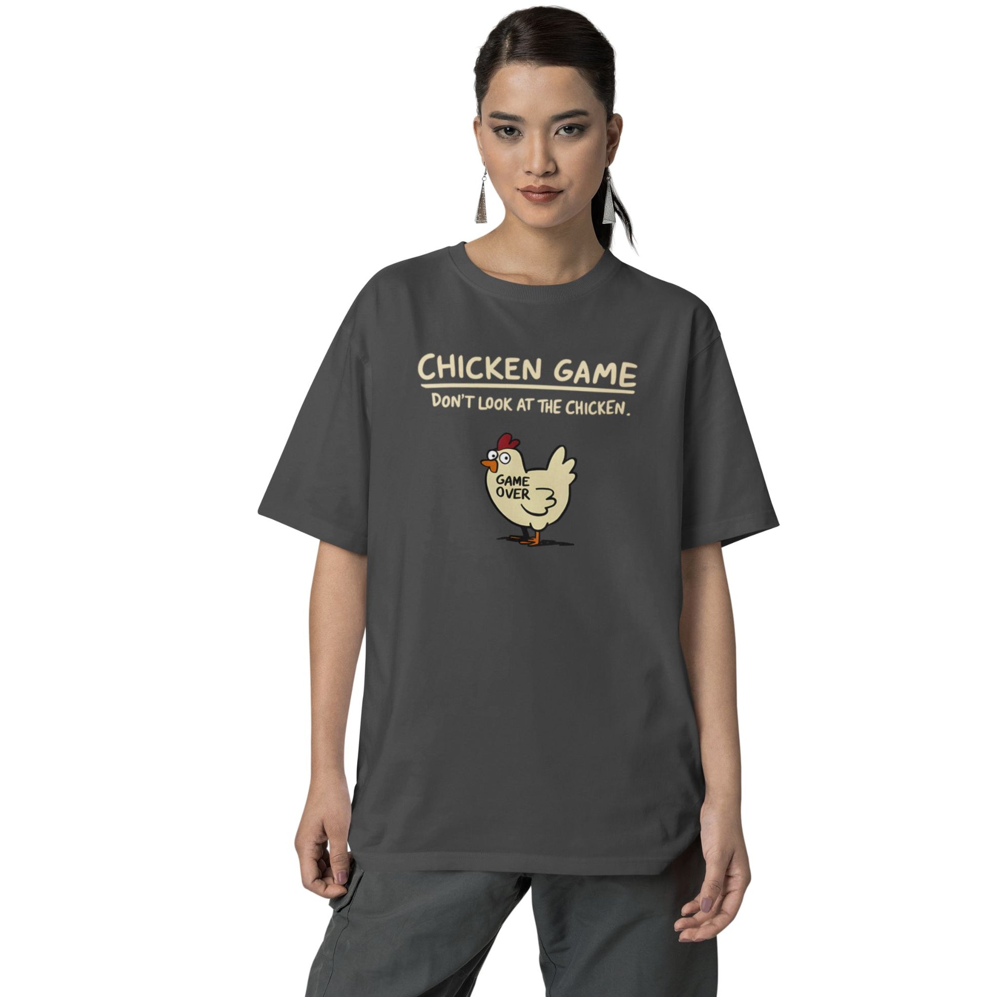 Frau trägt Unisex T-Shirt in Dunkelgrau mit Cartoon-Huhn und Spruch „Chicken Game – Don’t look at the chicken. Game Over“ – lustiges Shirt für Nerds & Partys