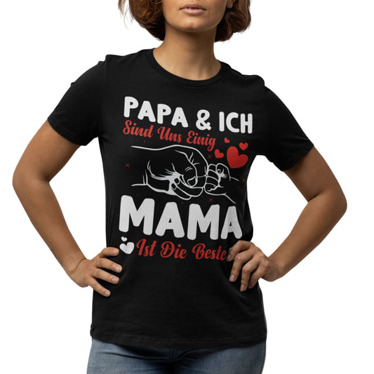 Frau trägt schwarzes T-Shirt mit weiß-rotem Aufdruck „Papa & ich sind uns einig – Mama ist die Beste“ und Fistbump-Motiv mit Herzchen
