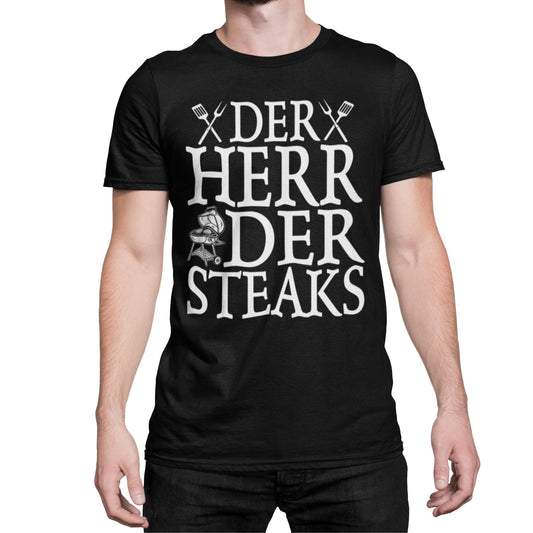 Mann trägt Schwarzes Unisex T-Shirt mit weißem Aufdruck „Der Herr der Steaks“ – lustiges Grillshirt mit BBQ-Motiv für Männer und Frauen