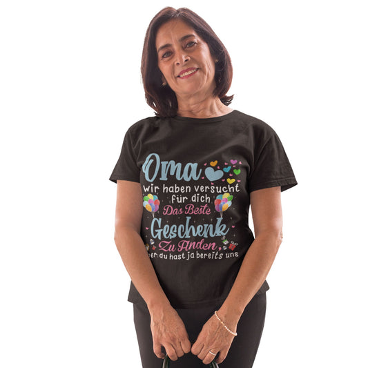 Ältere Frau trägt schwarzes T-Shirt mit buntem Aufdruck und dem humorvollen Text „Oma, wir haben versucht für dich das beste Geschenk zu finden, aber du hast ja bereits uns“