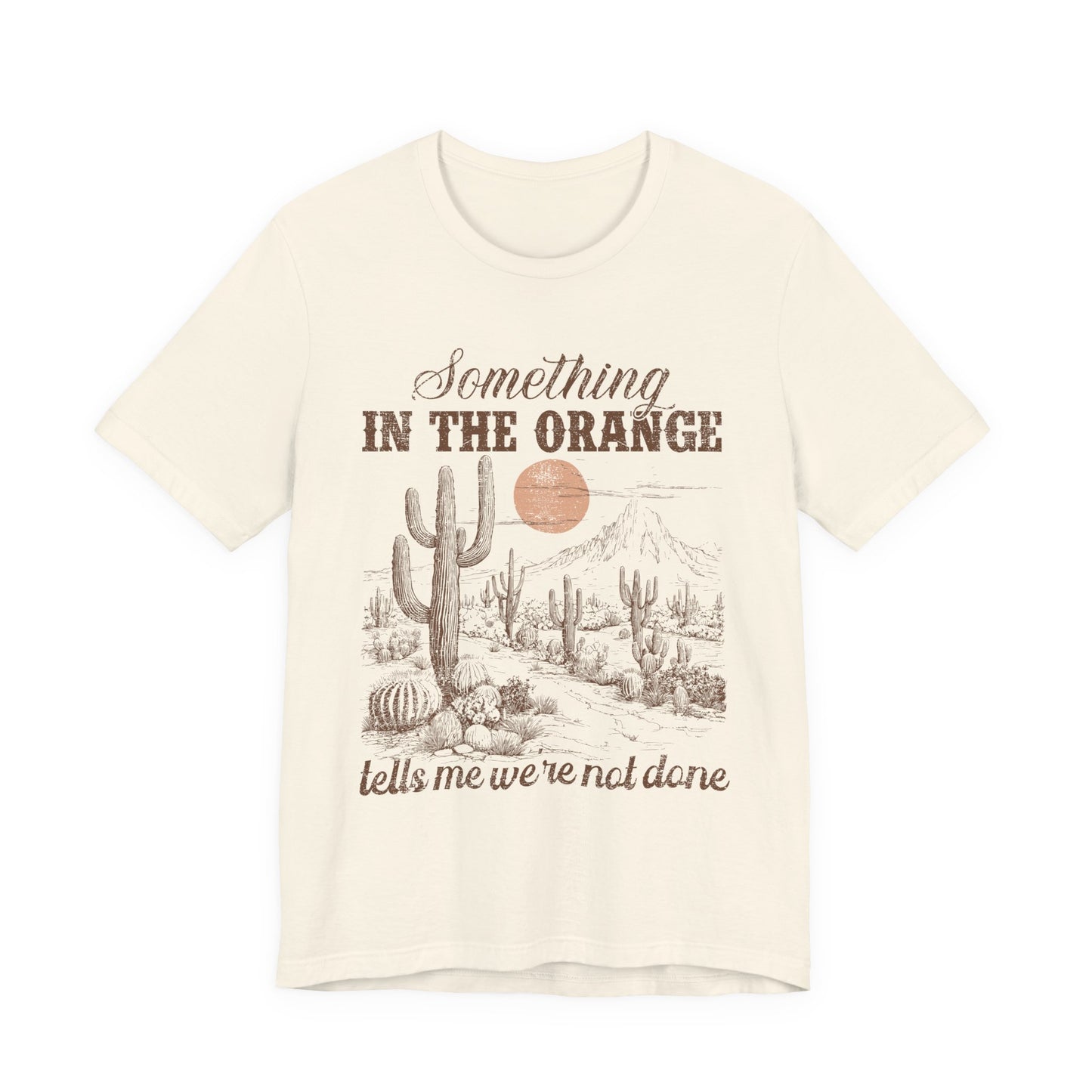 T-Shirt mit Spruch 'Something in the Orange tells me we’re not done' und Wüstenmotiv mit Kaktus & Sonnenuntergang – emotionales Country Shirt