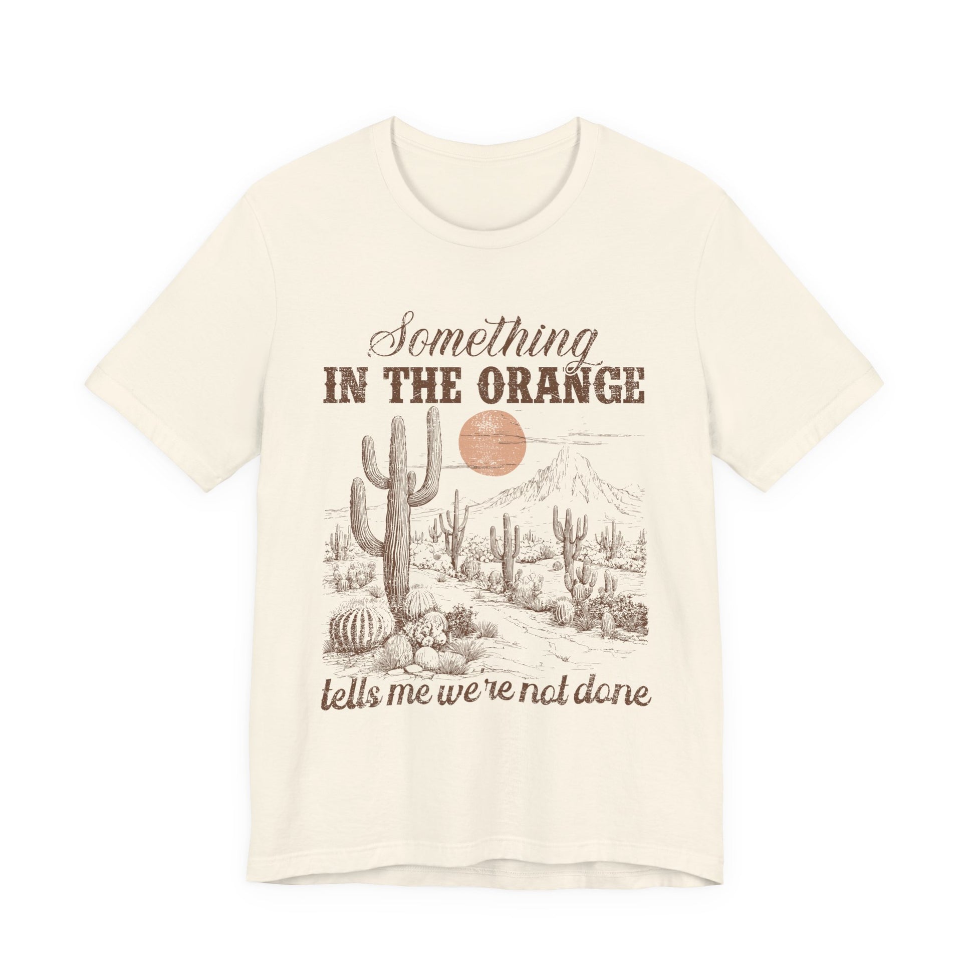 T-Shirt mit Spruch 'Something in the Orange tells me we’re not done' und Wüstenmotiv mit Kaktus & Sonnenuntergang – emotionales Country Shirt